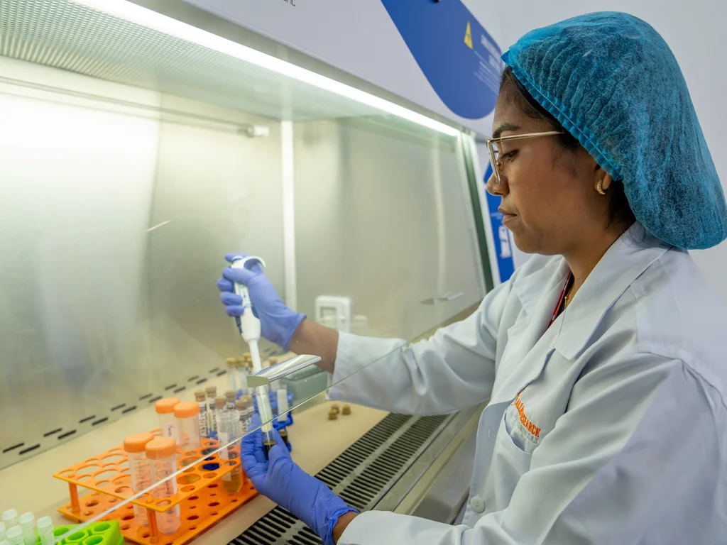Profesional de laboratorio trabajando con pipeta y tubos en una cabina de bioseguridad de Allied.