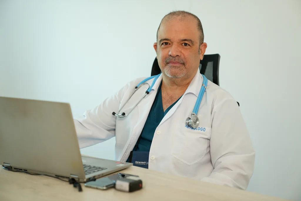 Allied physician seated at a computer in a consulting room.